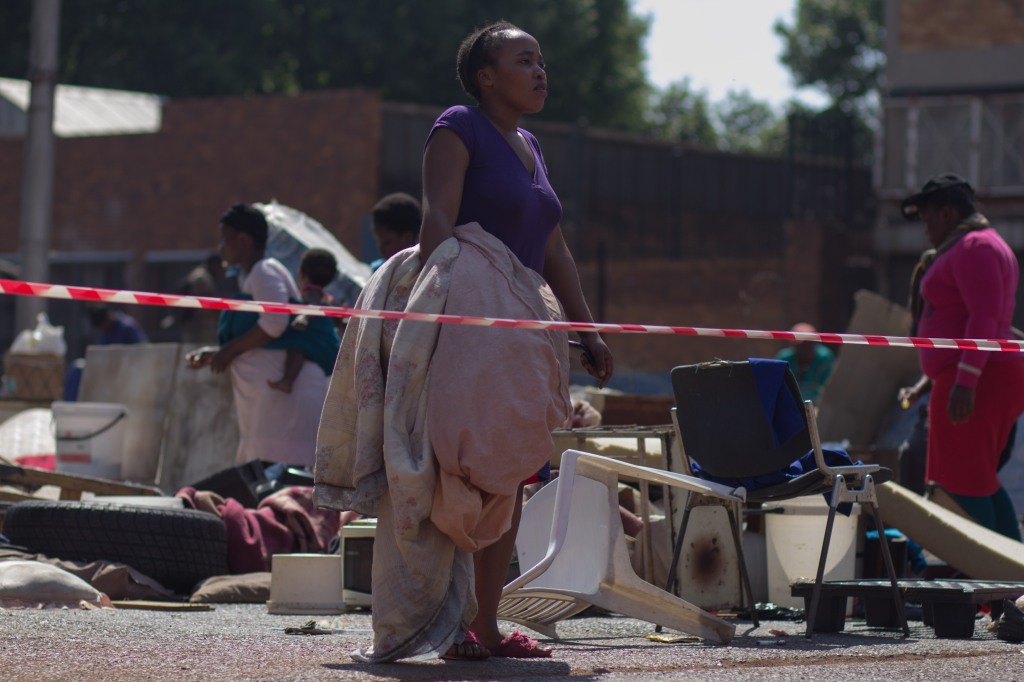 South Africa: A woman is seen holding bedding near the scene where residents were evicted from a building in downtown Johannesburg #Jeppestown on 29 September 2015. Residents of the building were #‎evicted following the handing down of a court order by the owner. The building was set alight by unknown individuals, leaving many homeless, as most of their belongings were still inside the burning building. © Jabulile Pearl Hlanze