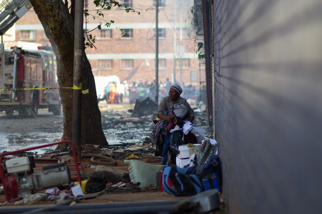 #SouthAfrica #Gauteng #Johannesburg #Joburg #SouthAfrica #Gauteng #Johannesburg #Joburg #Jeppestown #Reportage - A woman is seen carrying her belongings. Residents were evicted from a building in downtown Johannesburg #Jeppestown on 29 September 2015. Residents of the building were #evicted following the handing down of a court order by the owner. The building was set alight by unknown individuals, leaving many homeless, as most of their belongings were still inside the burning building. © Jabulile Pearl Hlanze