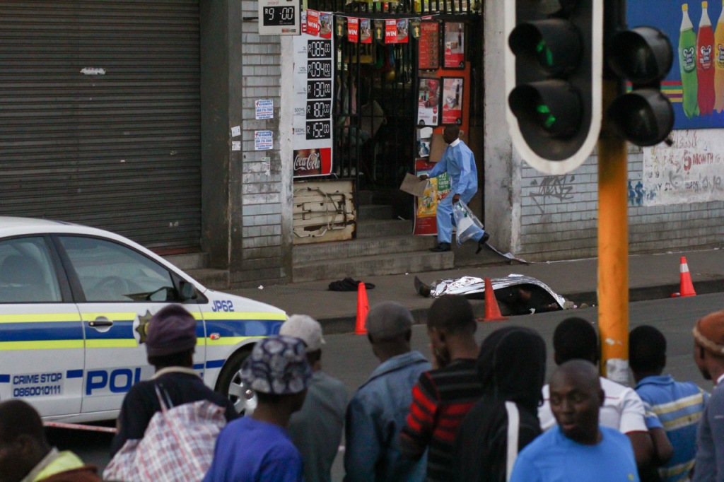 SOUTH AFRICA – JOHANNESBURG: A body of an unknown man lies on the pavement, as padestrians pass and stop to look on Rocky Street, Doornfontein, 02 September 2015. Peak hour traffic had to be re-routed to Sherwell Street, onto Siemert Road, in order to connect back on Rocky Street. Picture: Jabulile Pearl Hlanze