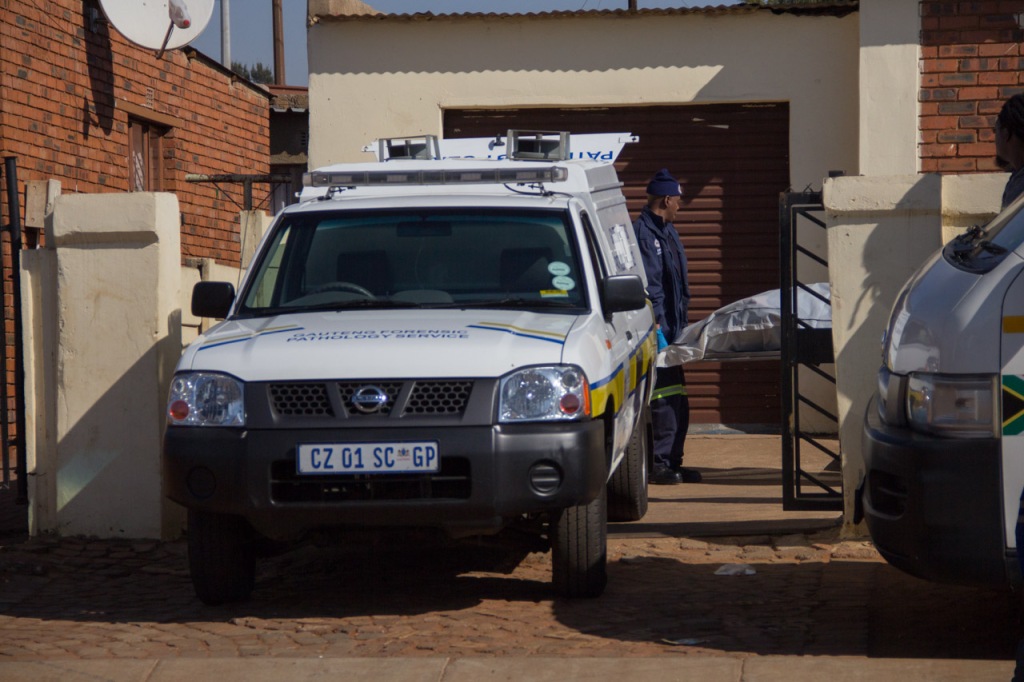 SOUTH AFRICA: A man is carried to the Gauteng Forensic Pathology Service van, after he was discovered by his mother in his backroom. His friends and family gathered outside his home as they watched the scene unfold in Mofokeng Section, Katlehong, Ekurhuleni. 19 June 2015. © JABULILE PEARL HLANZE